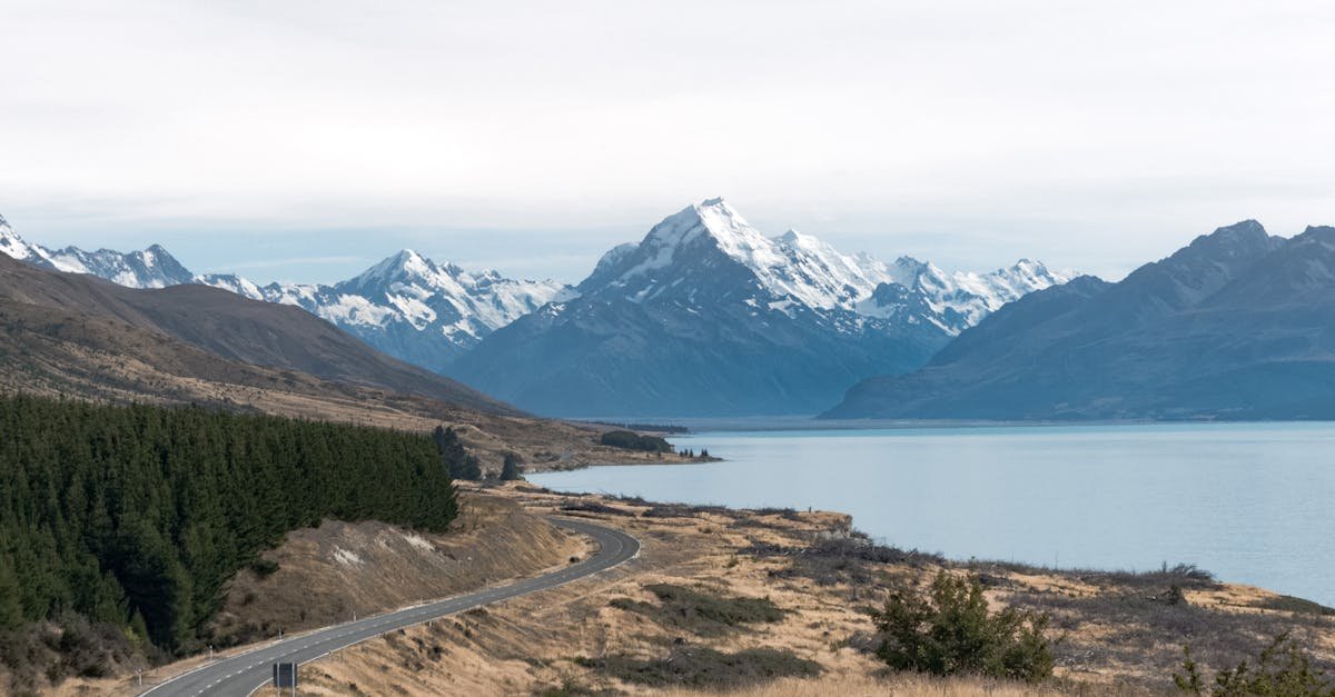 Breathtaking view of Mount Cook with a winding road, lake, and snow-capped peaks in New Zealand.
