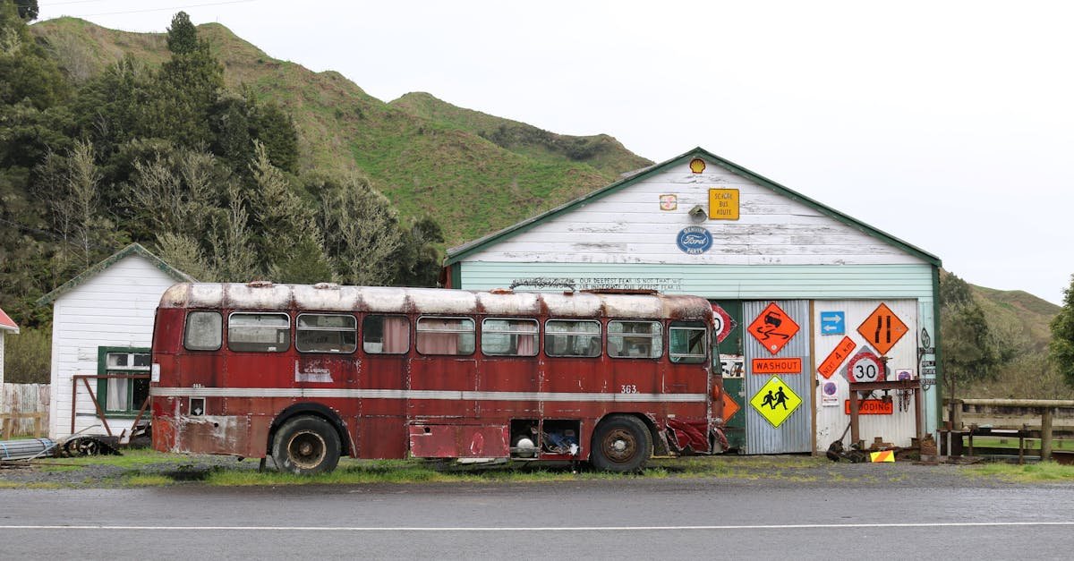 Explore the rustic charm of an abandoned red bus in scenic Whangamōmona, New Zealand.